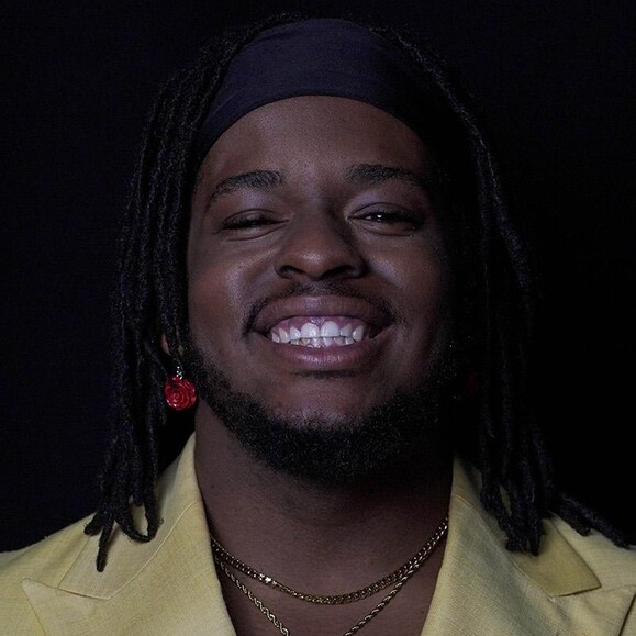 BARTLY smiling in a yellow jacket with layered necklaces