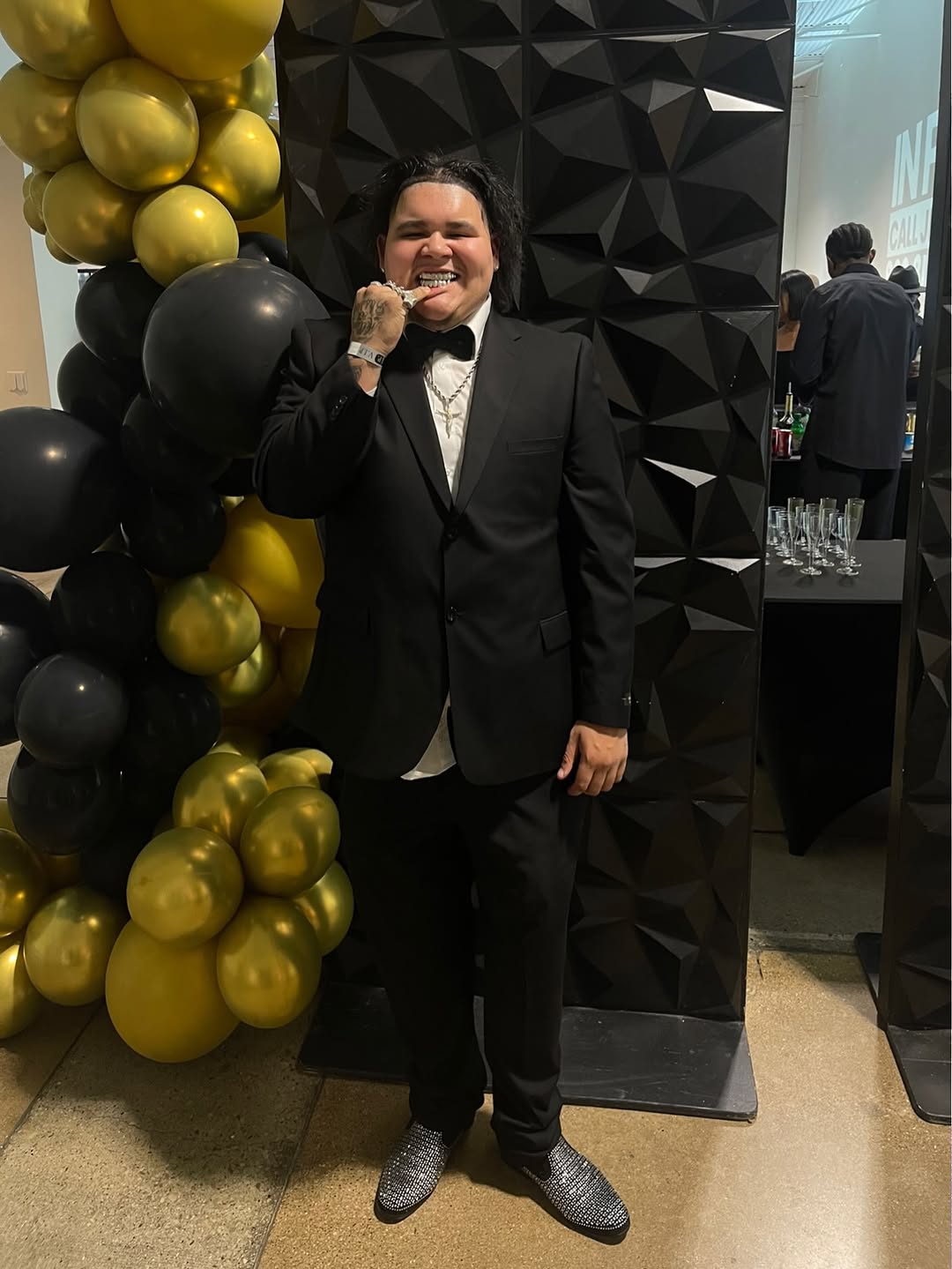 CFN Jizzle posing in a black suit at a formal event