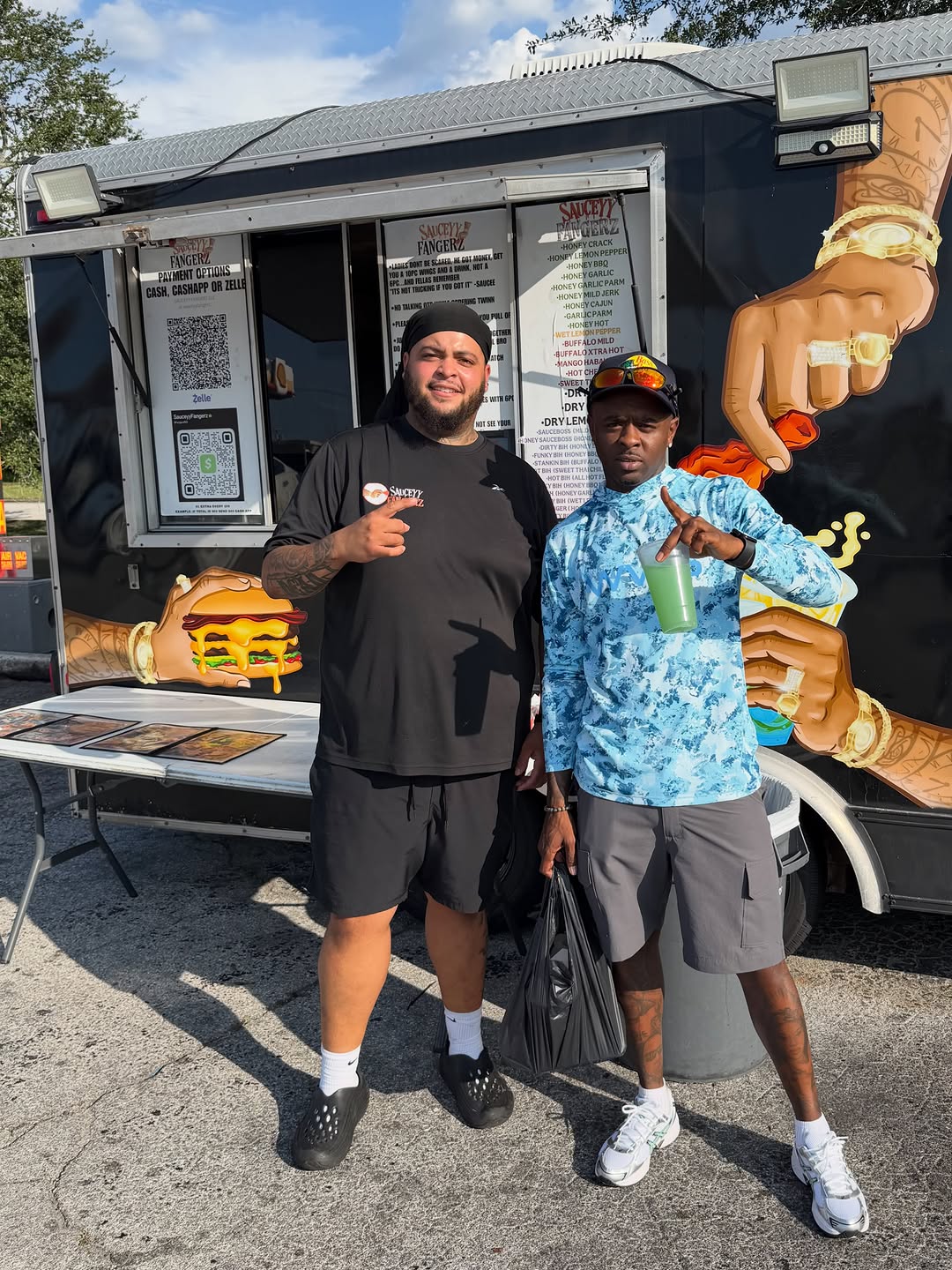 CFN Jizzle posing with a collaborator beside an outdoor food vendor