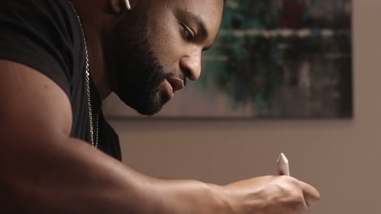 J French writing at a table in the official MERCI video