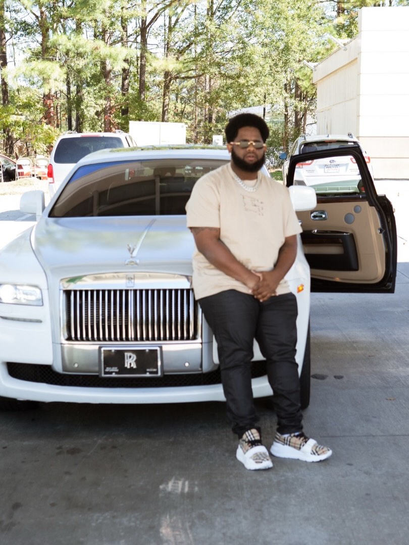 Juice The Mac standing in front of a white Rolls-Royce