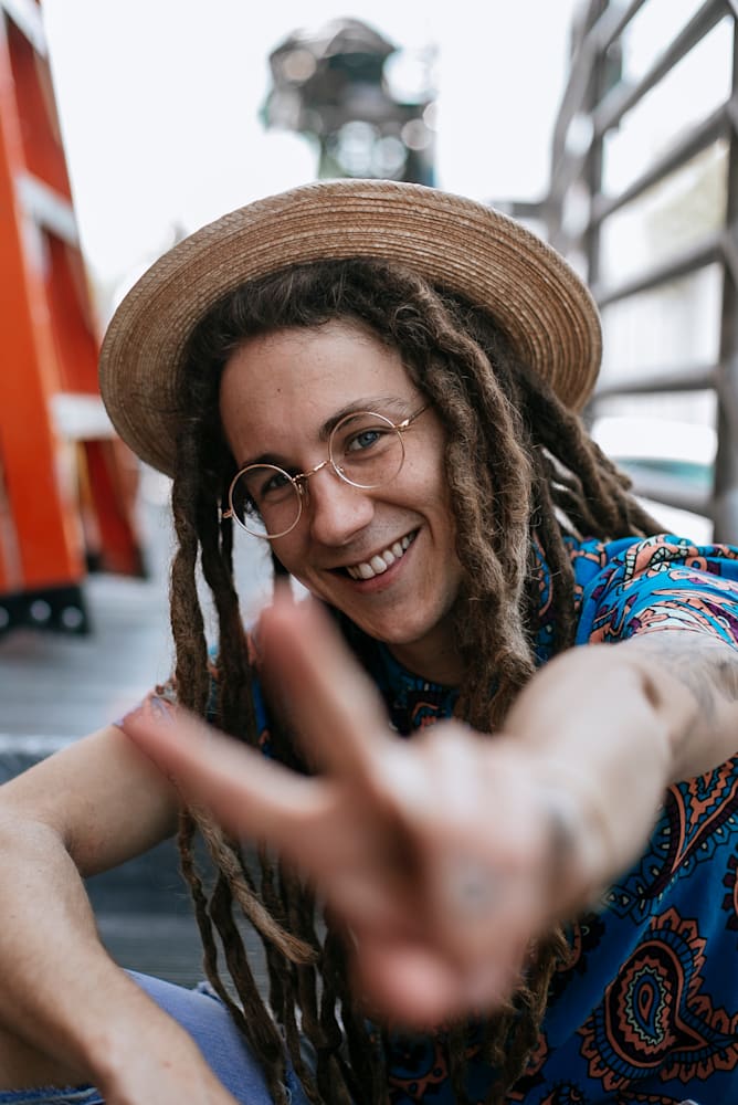 Kid Lennon smiling in a straw hat and blue patterned shirt