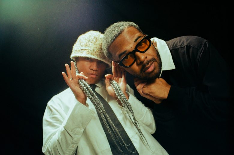 Magna Carda members Megz Kelli and Dougie Do posing together in a studio portrait