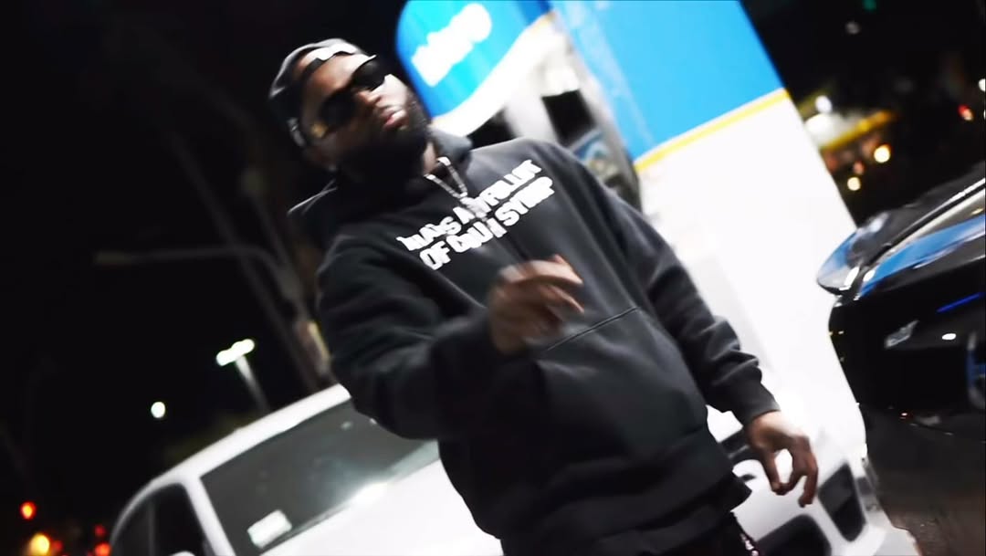 Mula XO standing beside a car at night in a black hoodie