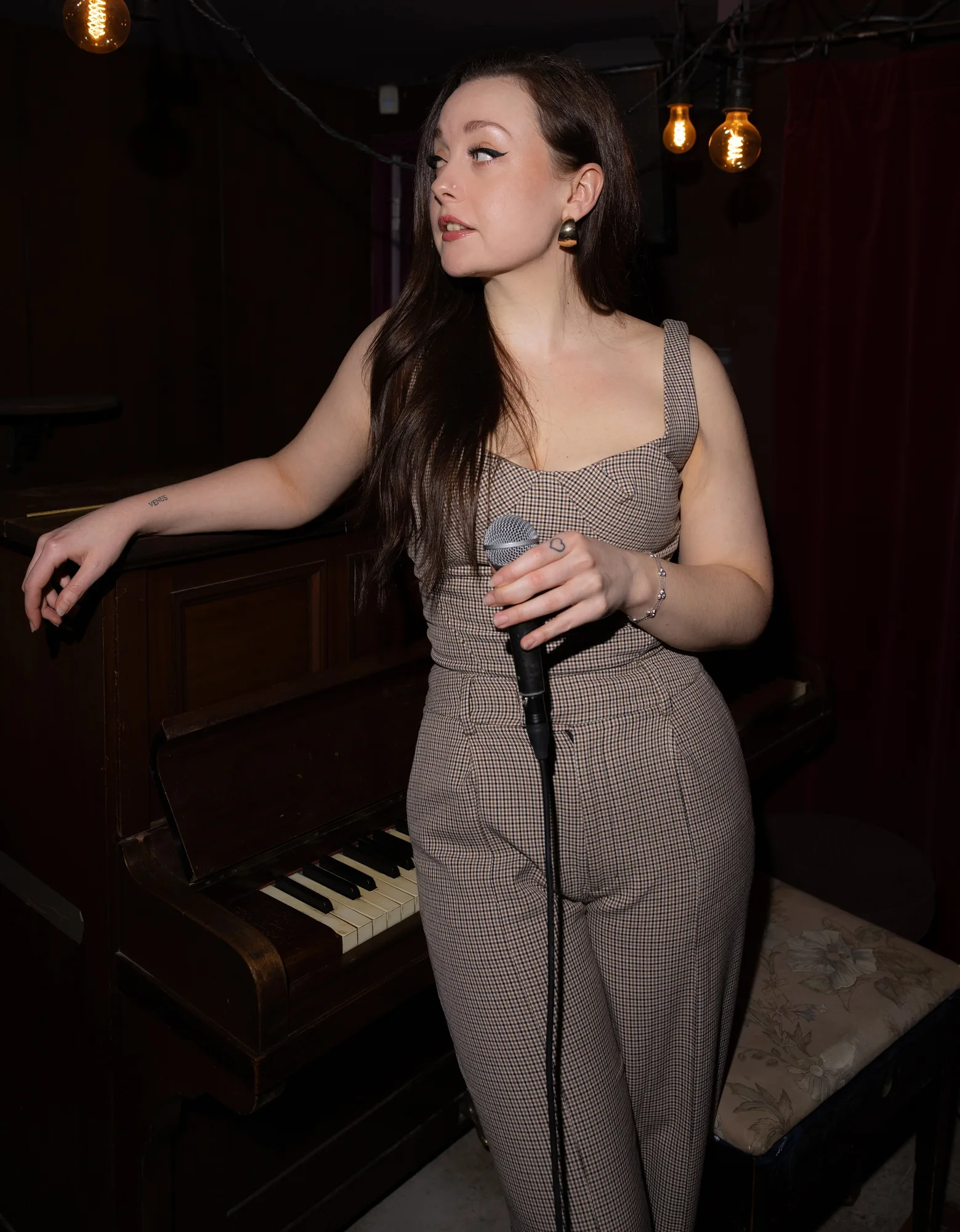 Scarlett Fagan holding a microphone beside a piano