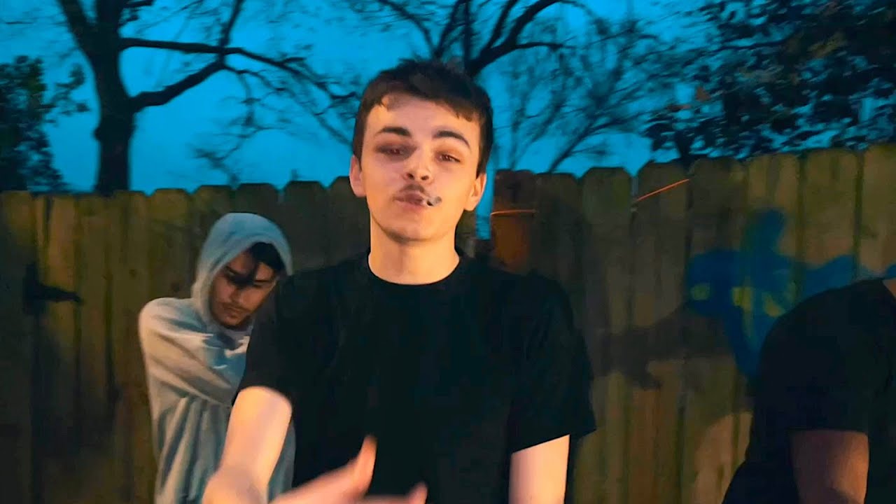Wiardon rapping outdoors in front of a wooden fence